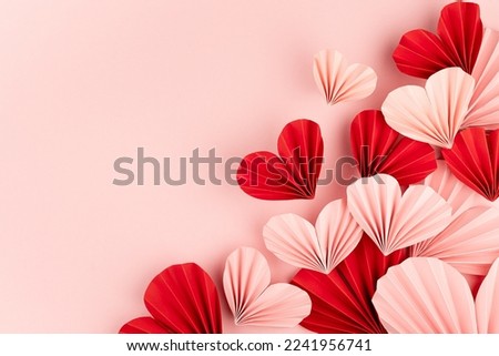 Valentines day, hearts love background for marriage celebration - many beautiful pink and red paper ribbed hearts in origami style fly on pastel pink color as sideways border, copy space, top view.  Royalty-Free Stock Photo #2241956741