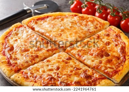 Freshly baked New York style pizza with melted mozzarella cheese and base tomato sauce close-up on a wooden board on the table. Horizontal
