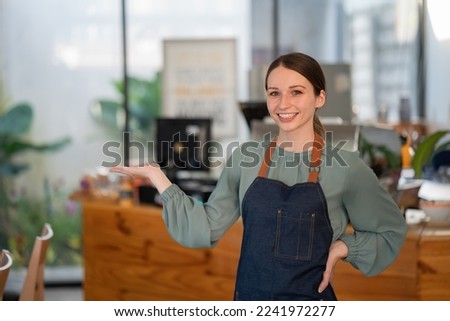 Businesswoman happy restaurant or cafeteria owner looking at the camera, a woman wearing an apron smiling and welcoming guests having a prosperous catering business concept.