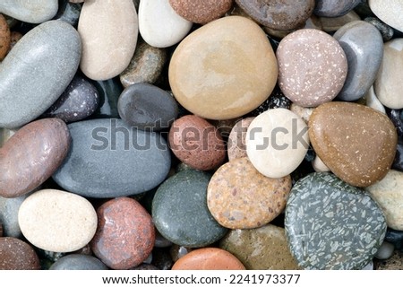 Smooth round wet pebbles texture background. Pebble sea beach close-up Royalty-Free Stock Photo #2241973377