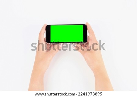 Young woman holding smartphone with green screen on white background, top view. Mockup for design