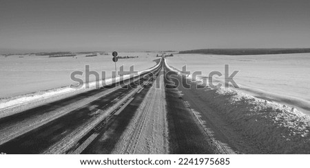 Winter road. Winter landscape of winding road. Snowy winter on the countryside, black and white picture. Highway leading through snowy fields. Drifts on the road.
Snowy road  of panoramic landscape.