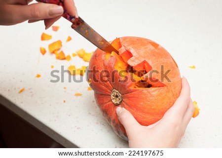 two hands cutting pumpkin on wooden desk