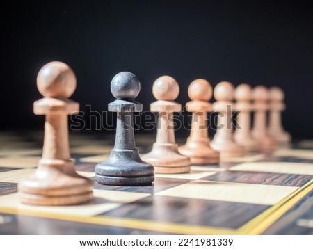 Black pawn standing in a row of white ones. Selective focus on the subject. The concept of otherness, dissimilarity, originality.
 Royalty-Free Stock Photo #2241981339
