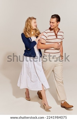 Young and beautiful man and woman in vintage style fashion clothes walking isolated over light background. 60s, 70s american culture concept. Retro fashion, relationship, love, emotions and ad Royalty-Free Stock Photo #2241984075