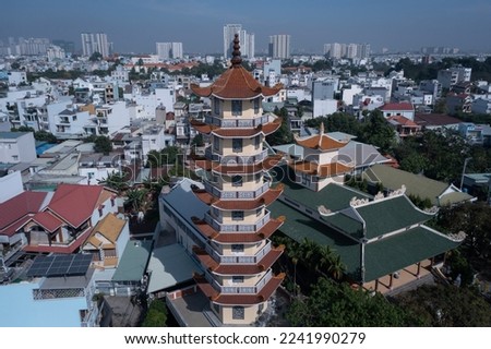 Buddhist temple and prayer tower in urban rooftop setting with view to city skyline on a sunny, clear day with blue sky. Close up shot.