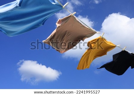 The wind blew clothes that had been dried in the sun and blown under the blue summer sky with cloud, symbolizing the work of housewives. Royalty-Free Stock Photo #2241995527
