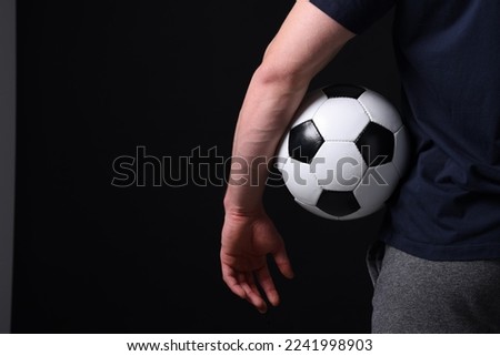 Athletic man with soccer ball on black background, closeup. Space for text