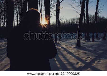 Man, with vapor coming from his mouth, in a forest on a cold sunny frosty day. 