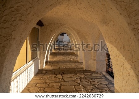 Sunlit archway with paved floor and plaster walls early in morning outside hotel building on resort