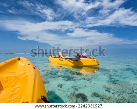 Travel concept - kayaking in sea at Maldives.
Yellow kayaks in blue sea at summer. Woman relaxing on floating canoe in clear azure water.  Royalty-Free Stock Photo #2242031527