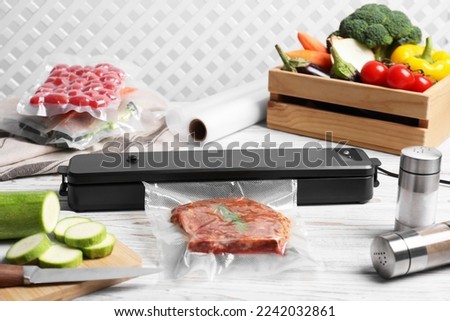 Sealer for vacuum packing and different food on white wooden table Royalty-Free Stock Photo #2242032861