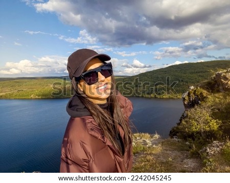 Traveler woman with hat and sunglasses  high above a blue lake .Traveling in the autumn  nature in Bulgaria	. Pchelina Lake 