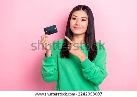 Photo of charming indonesian lady direct finger arm hold plastic debit card isolated on pink color background