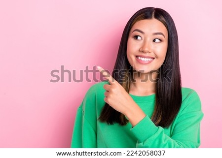 Photo of young wear green sweatshirt directing finger empty space young japanese lady look for new rent apartment isolated on pink color background