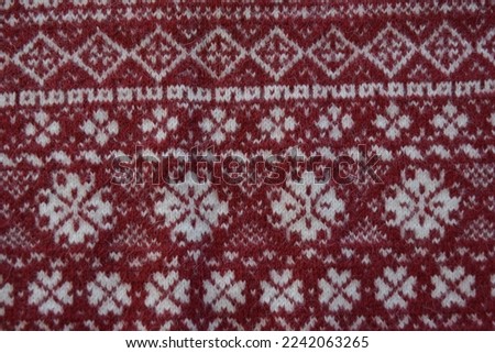 Beautiful knitted snowflake pattern. White snowflakes on a burgundy background.Suitable for background