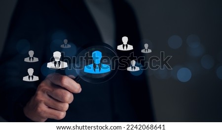 Human Resource Management HRM concept. Businessman holding magnifier for searching to human icons for human concept of development and recruitment, Find the right person for the company organization.