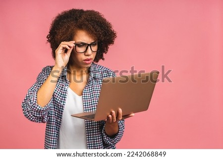 Young african american tired serious sad business woman with curly hair using laptop isolated over pink background.