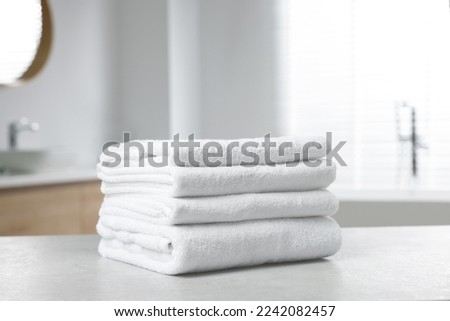 Stack of white towels on table in bathroom Royalty-Free Stock Photo #2242082457