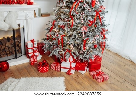 Beautiful Christmas gift boxes on floor near fir tree in room. High quality photo