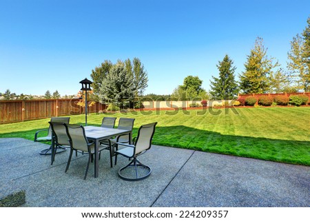 Patio area overlooking backyard landscape. Dining table with chairs and lantern