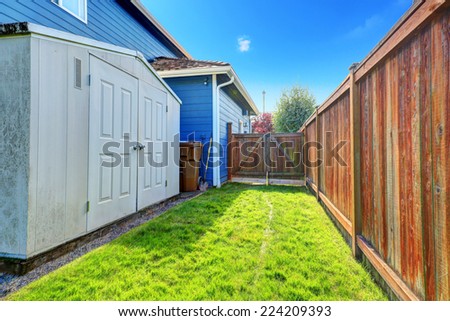Fenced backyard area with gate. Storage shed with white doors