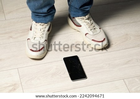 Man near dropped smartphone on floor, closeup. Device repairing