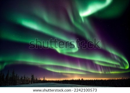 Northern lights over forest with sunset in the horizon  Royalty-Free Stock Photo #2242100573