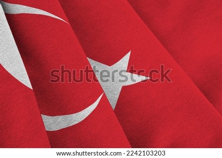 Turkey flag with big folds waving close up under the studio light indoors. The official symbols and colors in fabric banner