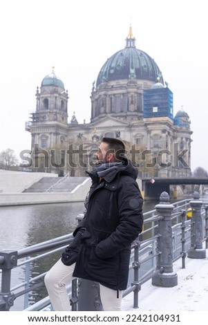 Young bearded male tourist, happily having his picture taken with the Berlin Cathedral in the background.