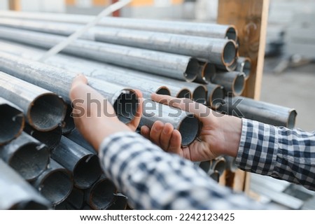 a worker holds metal pipes in a factory warehouse. Metal rolling.