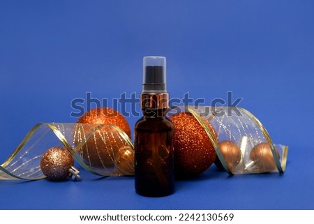 Cosmetic brown glass serum bottle with Christmas golden decorations. blue background with copy space