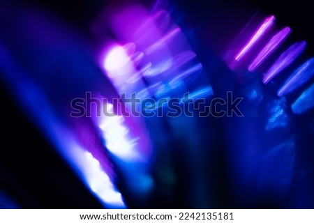 Blur neon light. Lens flare overlay. Bokeh fluorescent flash gleam. Defocused blue purple color flecks on dark black abstract background. Royalty-Free Stock Photo #2242135181