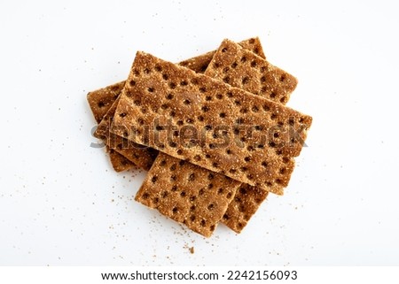 Slices of healthy low calories grain crisp bread for snack and crumbs on white background. Top view. Royalty-Free Stock Photo #2242156093