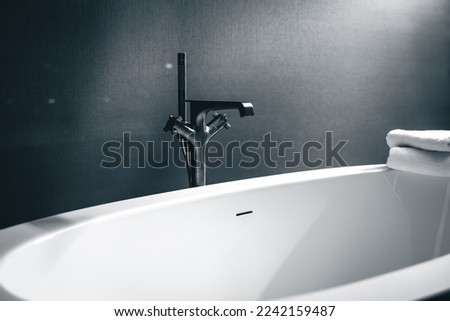 Steel faucet and bathtub in bathroom interior with window.