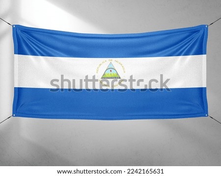 Nicaragua national flag cloth fabric waving on beautiful grey sky.