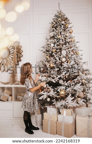A beautiful girl in a dress in a Christmas interior near a Christmas tree