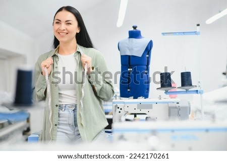 Positive young woman sewing with professional machine at workshop