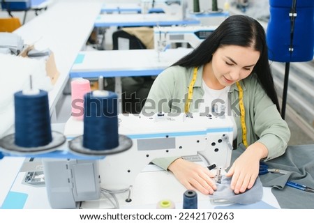Young woman working as seamstress in clothing factory Royalty-Free Stock Photo #2242170263