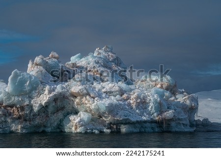 A LARGE MULTI COLORED FLOATING ICE CHUNK OFF OF SVALBARD NORWAY IN THE ARCTIC