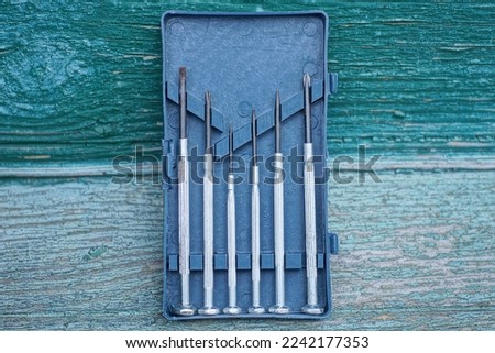 a set of gray black metal screwdrivers in a plastic open box on a green wooden table Royalty-Free Stock Photo #2242177353