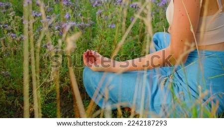 Meditation on flowers field. Woman relaxing. Lotus position. Breathing exercises.