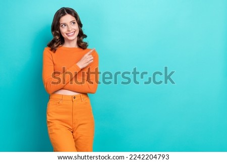 Photo portrait of cute young girl look curious point empty space dressed stylish orange outfit isolated on aquamarine color background