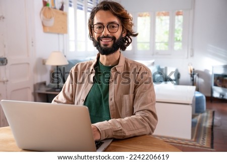 Cheerful young programmer looking at camera while working at his home. High quality photo