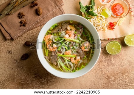 Vietnamese soup Pho with shrimps, onion and noodles on brown table top view Royalty-Free Stock Photo #2242210905