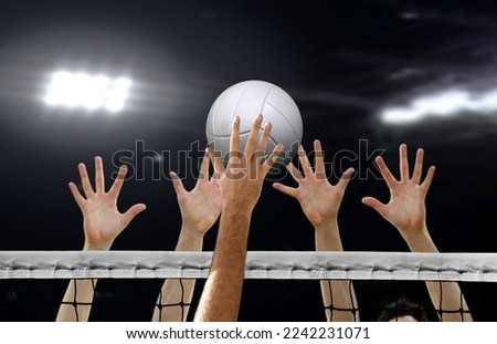 Volleyball spiking and hand blocking over the net under spotlights Royalty-Free Stock Photo #2242231071