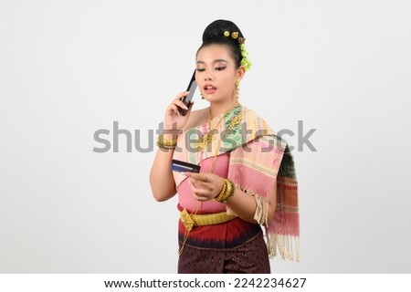 Portrait of Pretty Woman in Thai Northeastern Traditional Clothing with mobile phone and credit card, Pretty Asian woman in beautiful dress payment by credit card on smartphone on white background