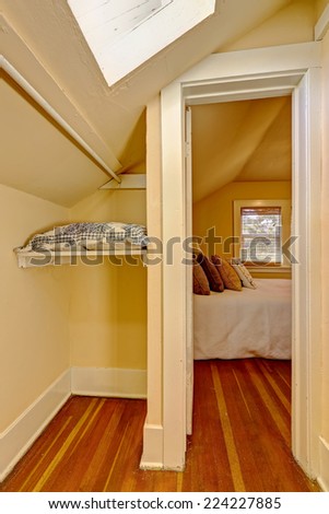Small empty walk in closet interior with vaulted ceiling and skylight.