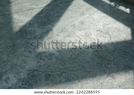 Rough cement floor shadows help with gray adhesion. The shiny surface reflects the rays of the afternoon sun with beautiful lines of shadows from the columns.