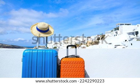 Summer concept with two luggage with hat and landscape view of Oia town in Santorini island in Greece , Greek landscape as blue sky background Royalty-Free Stock Photo #2242290223